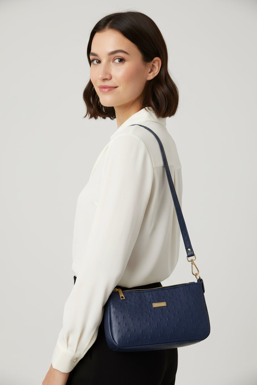 Navy blue ostrich vinyl shoulder bag with gold hardware and accents.  Two zippered pockets and one main compartment with magnetic closure.  Water resistant canvas lining.