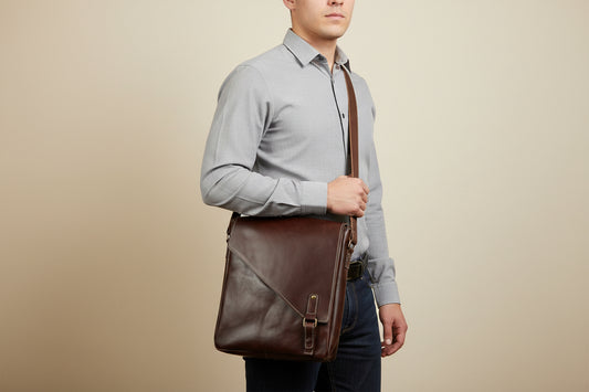 Beautiful red/brown leather messenger bag in an exciting vertical orientation.  Two zipper pockets front and back, leather tab magnetic flap closure.  Water resistant canvas lining in beige.  Adjustable 1.5 inch complimentary strap.  Antique brass hardware.